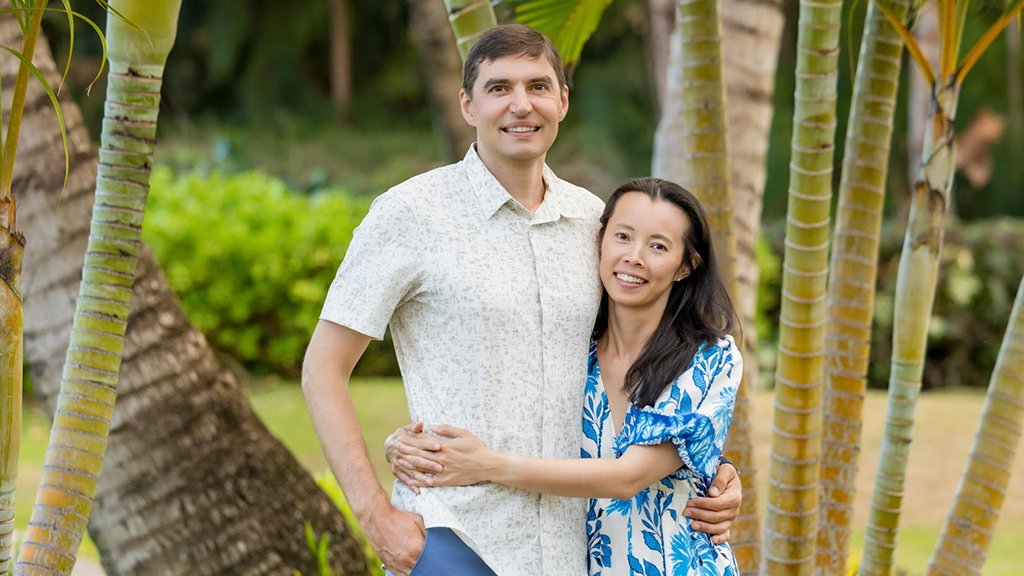 Vladimir Fedorov and Jean Wang standing facing camera with tropical trees in the background.