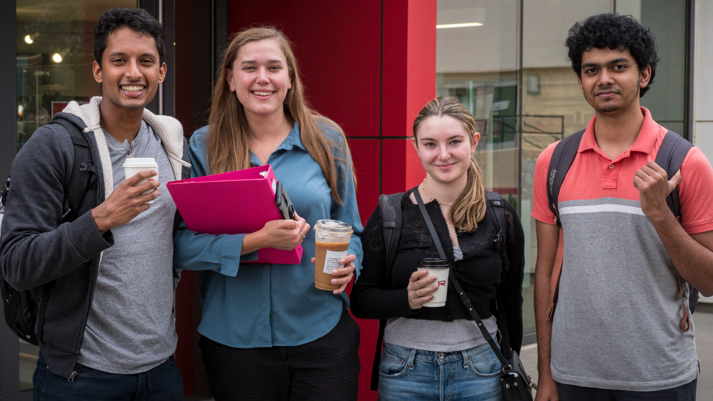 Four Caltech student smiling in front of the Red Door Cafe